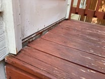 Wood deck A close up of a wood deck with a red staining on it next to a white wall.