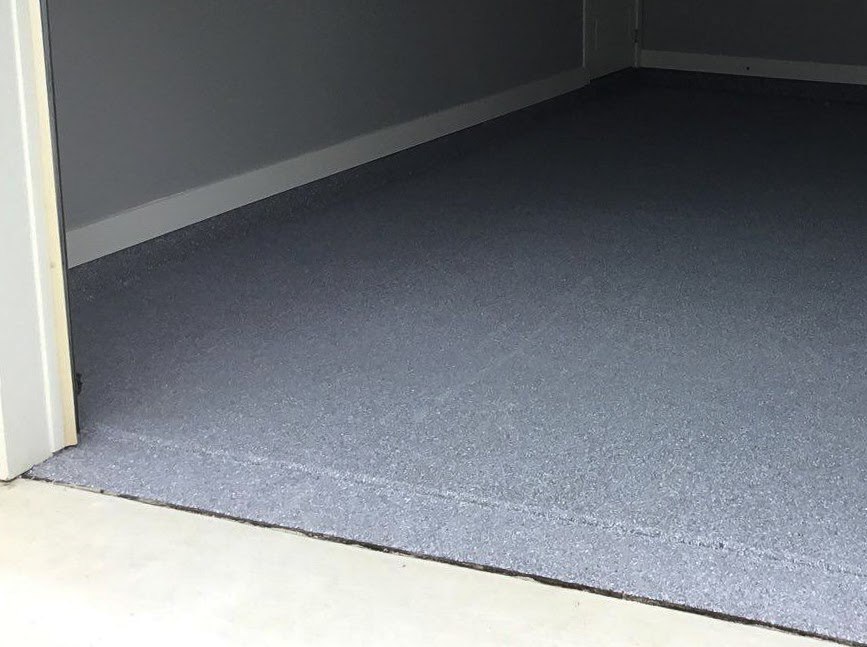 A garage floor with a blue colored coating that goes right outside the garage door.